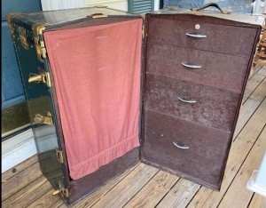 An open steamer chest with drawers.