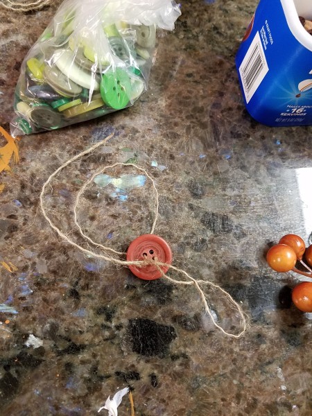 Lid Pumpkin Wall Hanging - putting twine through button holes