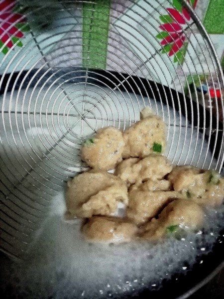 The partially cooked fish cakes being scooped out of the water.