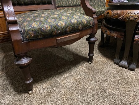 The legs of a wooden fabric covered chair.