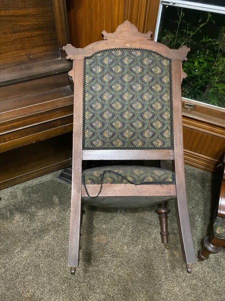 The back of a wooden fabric covered chair.