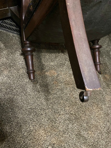 The wooden legs of a fabric covered chair.