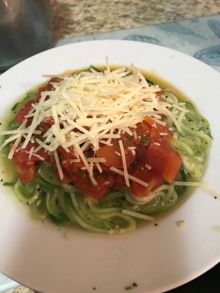 A completed dish of zucchini spiral noodles with fresh tomato sauce and cheese.