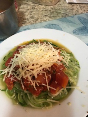 A completed dish of zucchini spiral noodles with fresh tomato sauce and cheese.