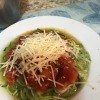 A completed dish of zucchini spiral noodles with fresh tomato sauce and cheese.