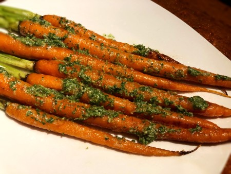 A plate of roasted carrots with carrot-top pesto.