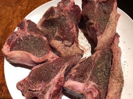 Uncooked lamb chops on a plate.