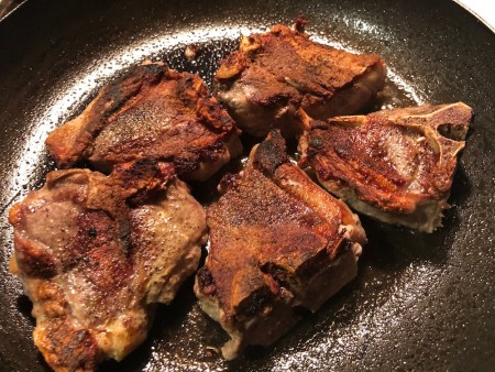 Cooking lamb chops in a frying pan.