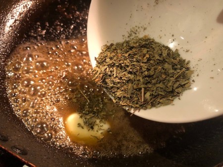 Herbs being added to melted butter.