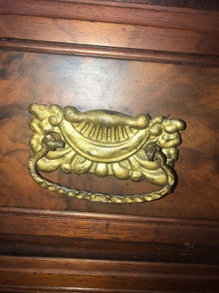 A metal pull on an antique dresser.