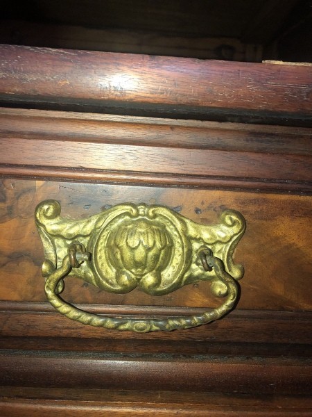 A metal pull on an antique dresser.