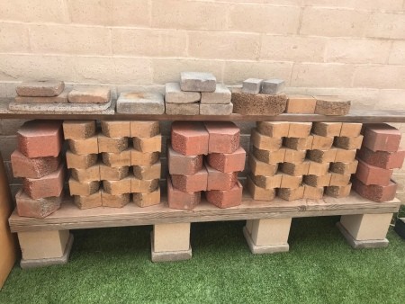 A low shelf on concrete blocks with other bricks stored above.