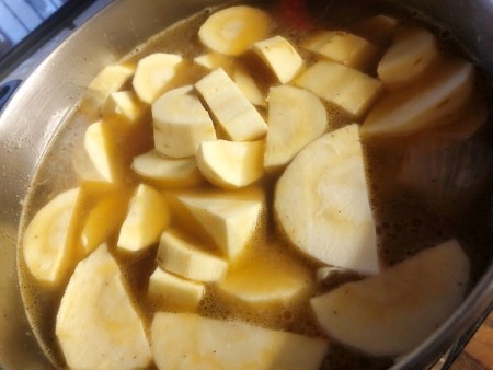 Chopped parsnips being added to a stock pot.