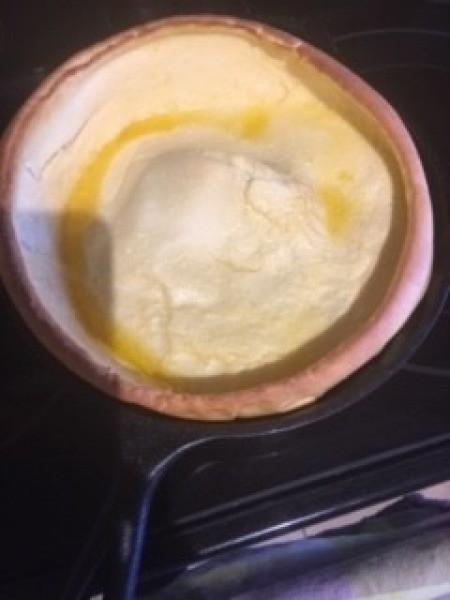 A cooking Dutch Baby in a pan.