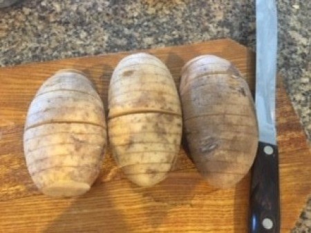 Three potatoes sliced partially through.