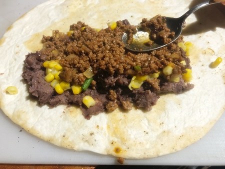 Adding ground beef to the tortilla.