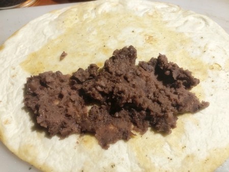 Adding beans to the tortilla.