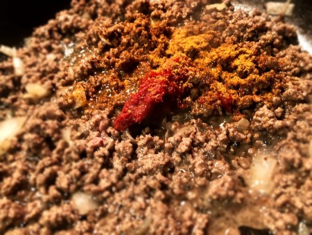 Adding spices to the ground beef.