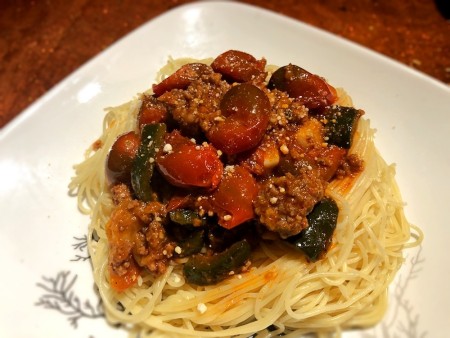 A plate of pasta topped with cherry tomato bolognese.