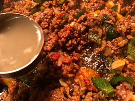 Adding stock to the ground beef mixture.