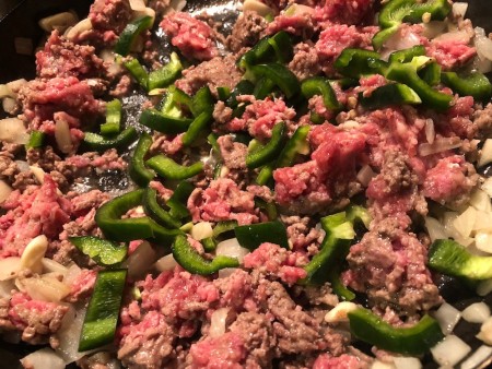 Ground beef and peppers being sauteed in a pan.