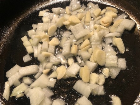 Onions and garlic being sauteed in a pan.