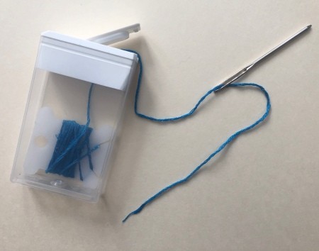 A Tic-tac container with embroidery floss stored inside.
