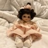 Identifying a Porcelain Doll? - small dark haired doll wearing a pink dress