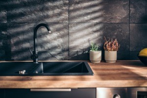 A black kitchen sink with a wooden countertop.