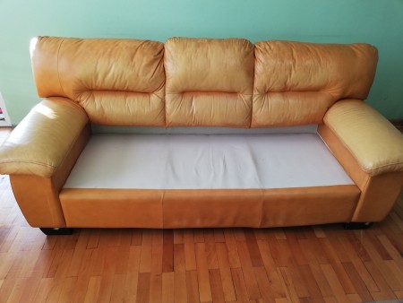 A leather sofa with the cushions removed.