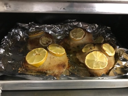 The baked chicken pieces with lemon on top.