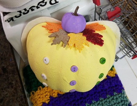 Non-Traditional Foam Pumpkin Halves - closeup of finished yellow pumpkin with purple mini pumpkin and fall leaves glued to the top and three rows of buttons in the colors of the other pumpkins