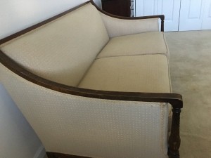 A white couch with wooden trim.