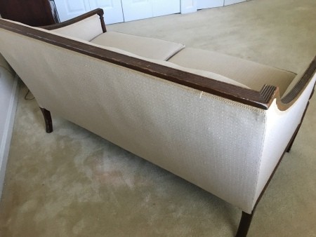 A white couch with wooden trim.