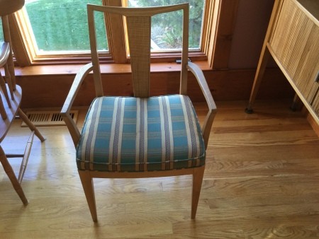 A dining room chair with a plaid seat.