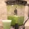 The blended green juice in a blender and in a cup.