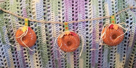 Mini Baking Tin Pumpkins - pumpkins strung on robe in front of a crochet afghan