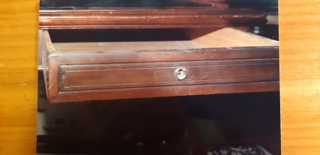 An open drawer of a wooden desk.