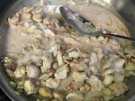 Adding curry sauce to the cooked chicken.