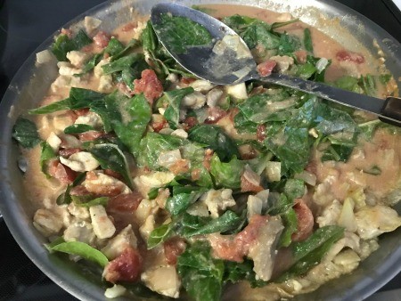 Adding Swiss chard to the chicken curry mixture.