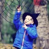 A child wearing a witch hat next to a yarn spiderweb.
