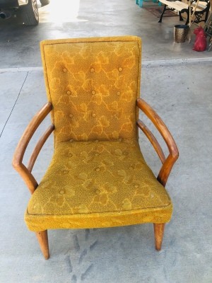 A vintage chair in upholstered in yellow-gold fabric.