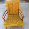 A vintage chair in upholstered in yellow-gold fabric.