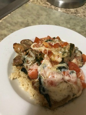 A plate of Caprese chicken severed over rice.