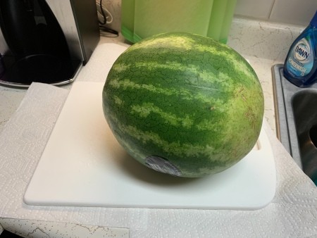 A whole watermelon on a cutting board.