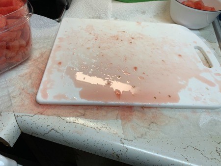 A cutting board with watermelon juice.