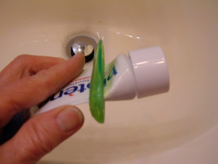 Squeezing the toothpaste to the top of the tube.
