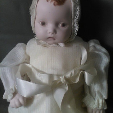 A bisque baby doll with brown hair.