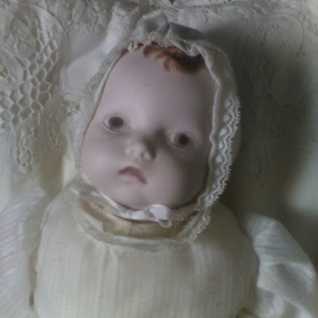 A bisque baby doll with brown hair.