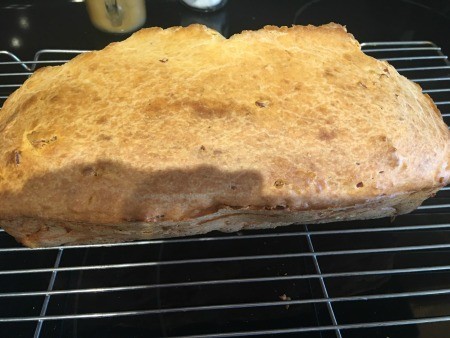 A loaf of pepperoni cheese bread on a cooling rack.